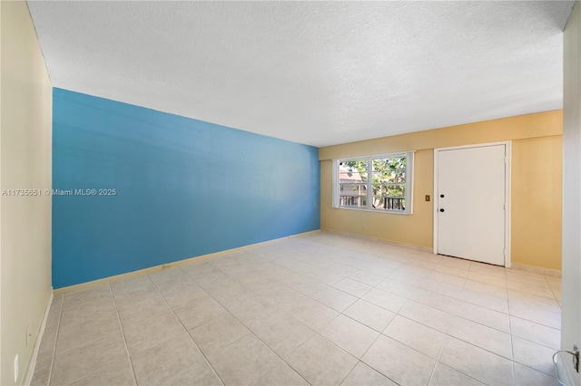 tiled empty room featuring a textured ceiling