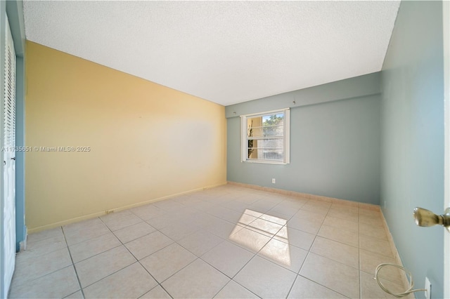 spare room with a textured ceiling and light tile patterned flooring