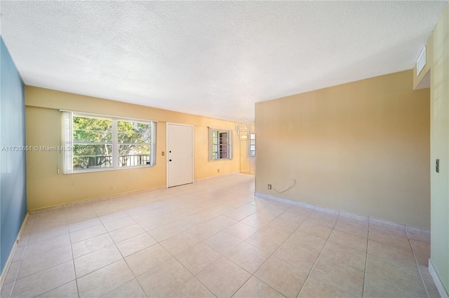 spare room featuring light tile patterned floors and a textured ceiling