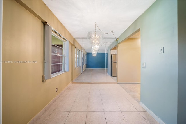 hallway featuring light tile patterned flooring and a notable chandelier