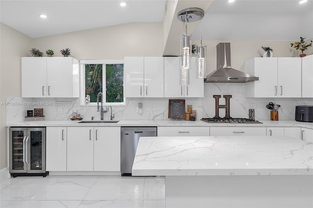 kitchen featuring wine cooler, hanging light fixtures, appliances with stainless steel finishes, wall chimney range hood, and white cabinets