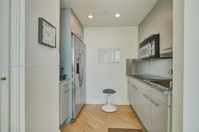 kitchen with white cabinetry, black electric cooktop, stainless steel fridge, and light wood-type flooring