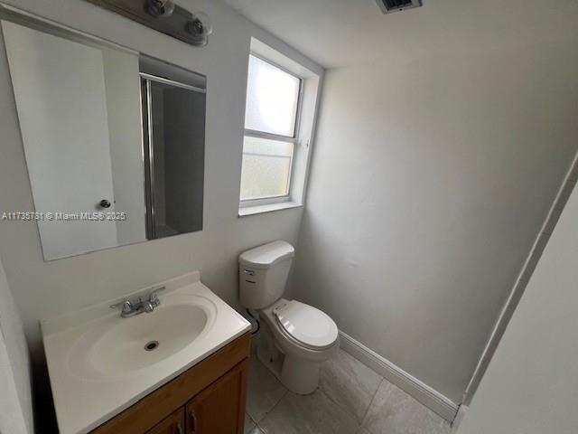 bathroom with walk in shower, tile patterned floors, vanity, and toilet