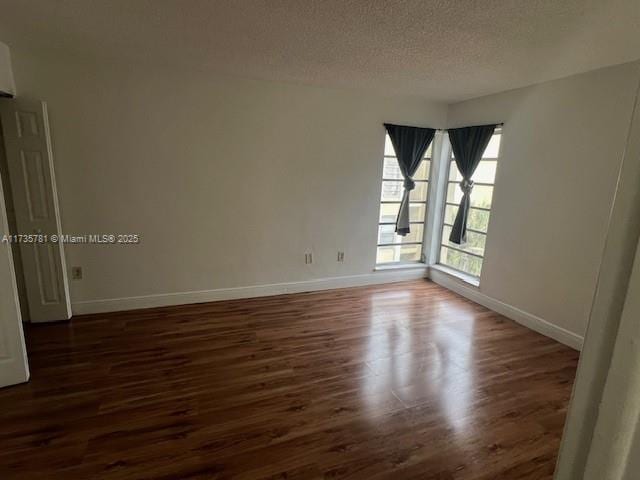 spare room featuring dark hardwood / wood-style floors and a textured ceiling