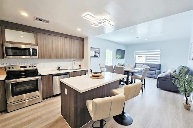 kitchen with a breakfast bar, modern cabinets, visible vents, and appliances with stainless steel finishes