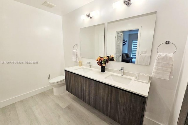 full bathroom with visible vents, toilet, wood finished floors, and a sink