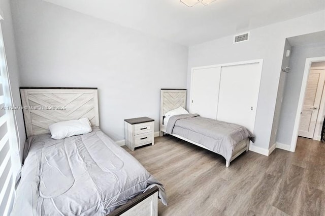 bedroom featuring visible vents, baseboards, a closet, and wood finished floors