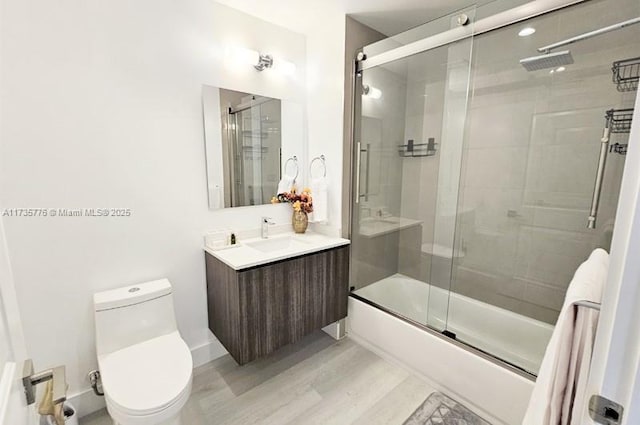 full bath with vanity, toilet, wood finished floors, and bath / shower combo with glass door