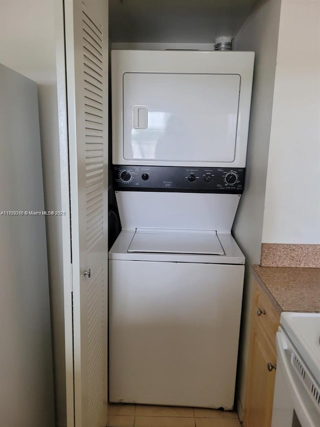 clothes washing area with stacked washer / drying machine and light tile patterned floors