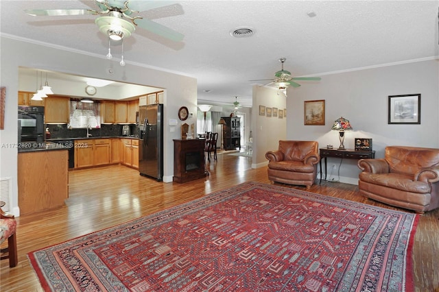 living room with crown molding, light hardwood / wood-style flooring, and a textured ceiling