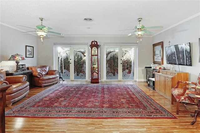 living room with crown molding, hardwood / wood-style floors, ceiling fan, and a textured ceiling