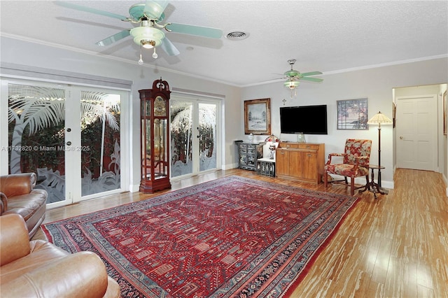 living room with hardwood / wood-style floors, ornamental molding, french doors, and a textured ceiling