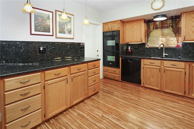 kitchen featuring tasteful backsplash, light wood-style flooring, black appliances, pendant lighting, and a sink