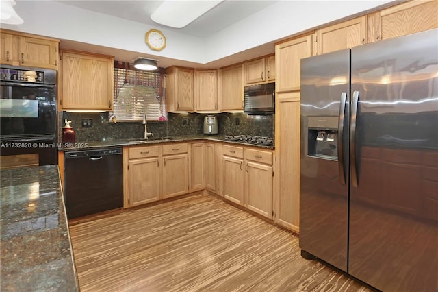 kitchen featuring tasteful backsplash, sink, dark stone countertops, light hardwood / wood-style floors, and black appliances