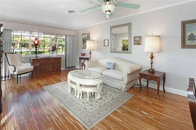 living room featuring crown molding, ceiling fan, wood-type flooring, and a textured ceiling