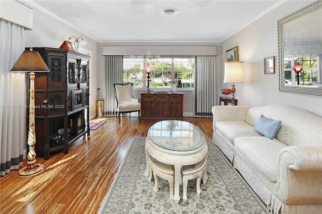 living room featuring wood-type flooring, ornamental molding, and a textured ceiling