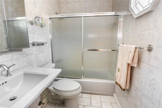 full bathroom with sink, shower / bath combination with glass door, tile walls, tile patterned floors, and toilet