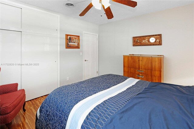 bedroom featuring ceiling fan, hardwood / wood-style flooring, a closet, and a textured ceiling