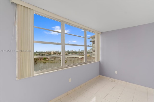 empty room featuring light tile patterned floors and a water view