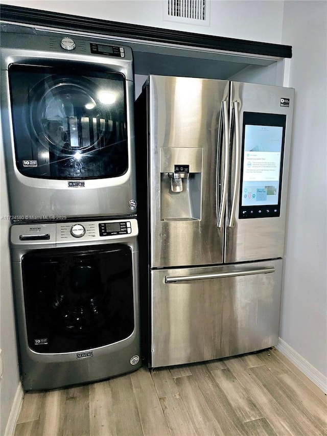 kitchen with stacked washer and dryer, stainless steel fridge with ice dispenser, and light hardwood / wood-style flooring