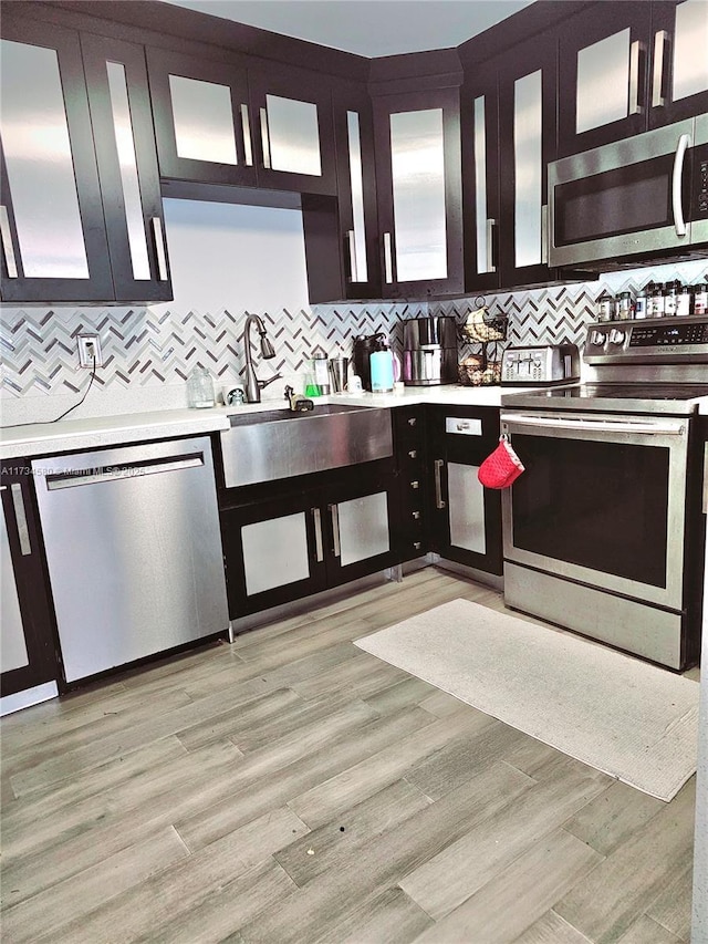 kitchen with backsplash, stainless steel appliances, and light wood-type flooring