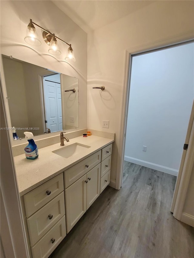 bathroom with baseboards, wood finished floors, and vanity