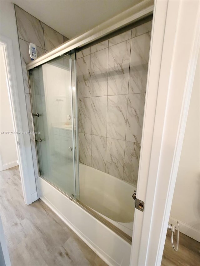 full bath with enclosed tub / shower combo, baseboards, and wood finished floors