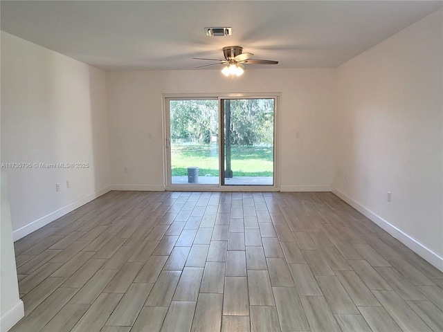 empty room featuring a ceiling fan, light wood-style flooring, visible vents, and baseboards