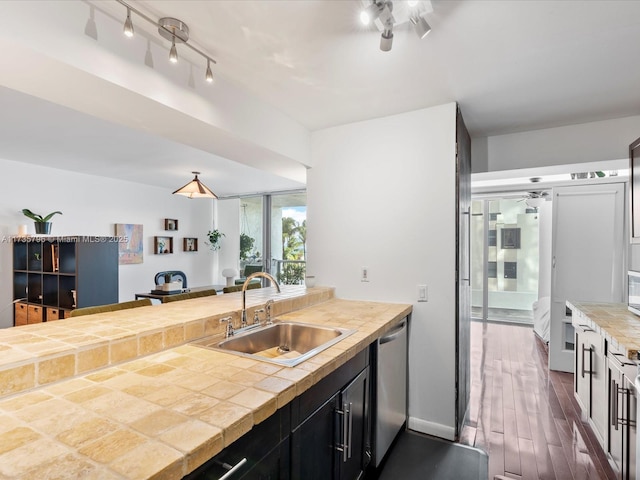 kitchen with dark wood-type flooring, rail lighting, sink, tile counters, and dishwasher