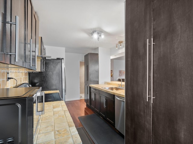 kitchen featuring appliances with stainless steel finishes, wood-type flooring, sink, decorative backsplash, and dark brown cabinets