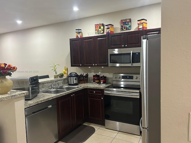 kitchen with light stone counters, stainless steel appliances, sink, and light tile patterned floors