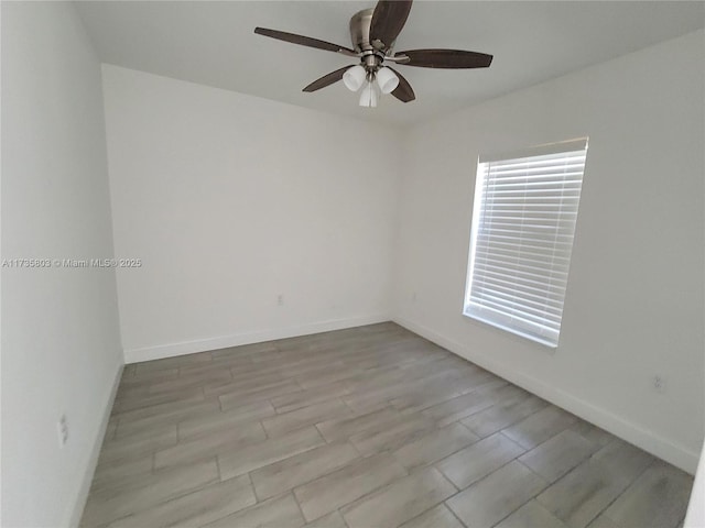 spare room with a ceiling fan, light wood-style flooring, and baseboards