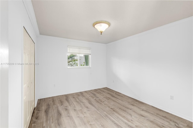 spare room with ornamental molding and light hardwood / wood-style floors