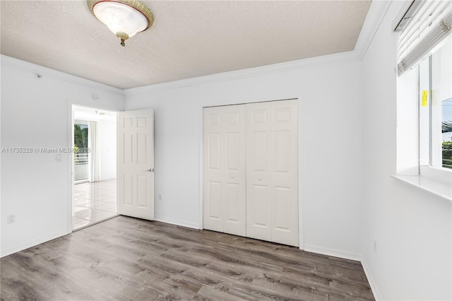 unfurnished bedroom featuring wood-type flooring, ornamental molding, a closet, and a textured ceiling