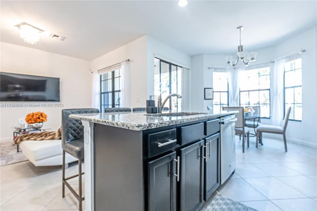 kitchen featuring pendant lighting, sink, dishwasher, an island with sink, and a kitchen bar