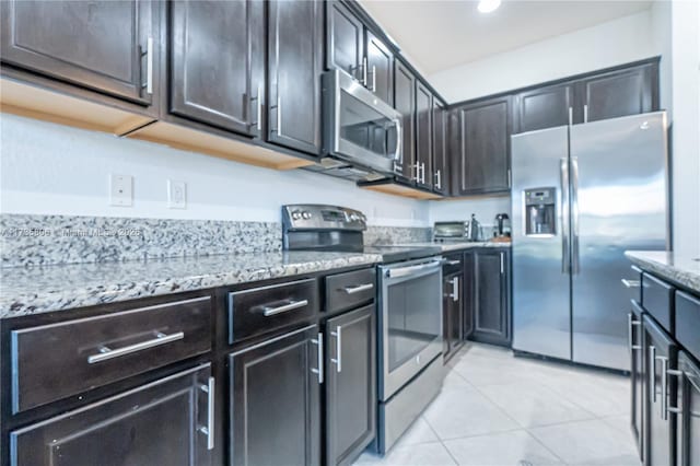 kitchen featuring stainless steel appliances, light stone countertops, and light tile patterned floors