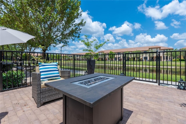 view of patio with a fire pit and a water view