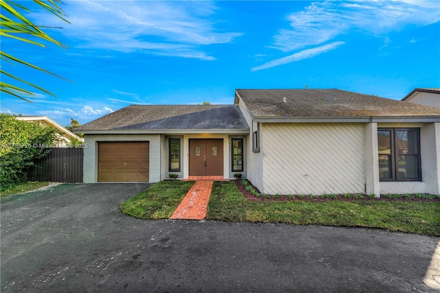 view of front of home with brick siding, a shingled roof, an attached garage, fence, and driveway