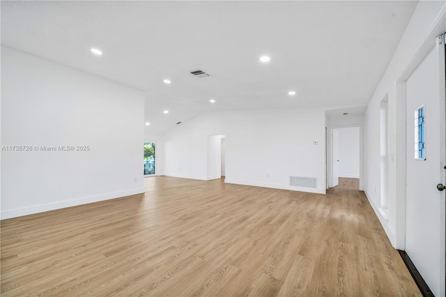 unfurnished living room featuring vaulted ceiling and light wood-type flooring