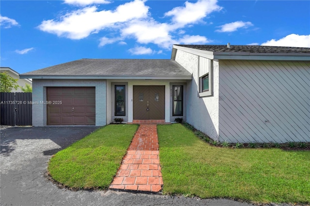 view of front facade with aphalt driveway, brick siding, roof with shingles, an attached garage, and a front lawn