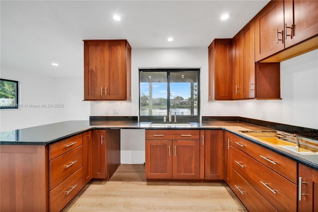 kitchen with sink, light wood-type flooring, and kitchen peninsula