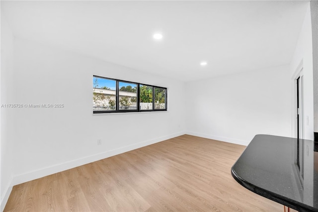 spare room featuring recessed lighting, light wood-type flooring, and baseboards