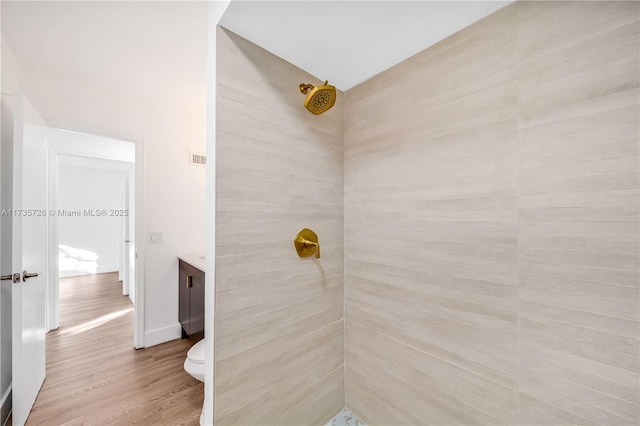 full bath with toilet, wood finished floors, visible vents, vanity, and tiled shower