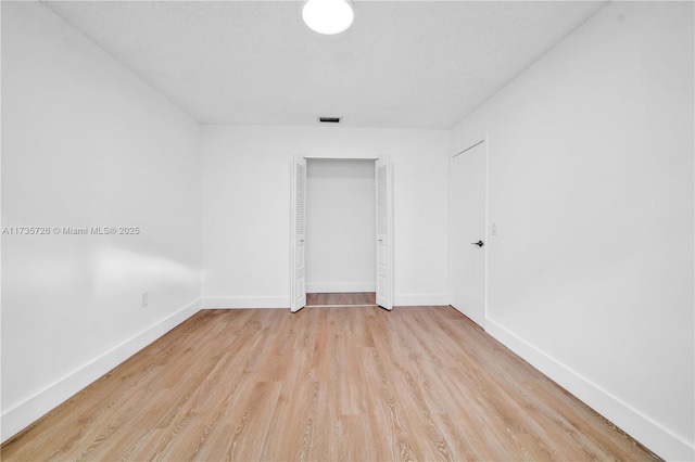 spare room featuring visible vents, light wood-style flooring, and baseboards