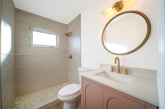 bathroom with vanity, toilet, and tiled shower