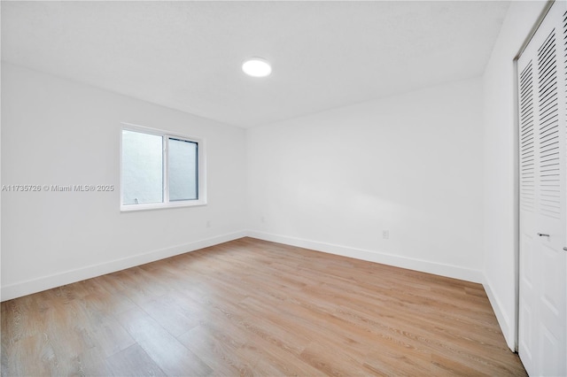 unfurnished bedroom with a closet, baseboards, and light wood finished floors