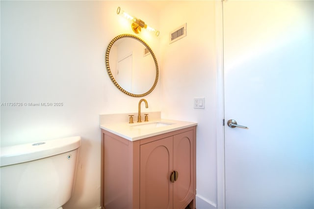 bathroom with visible vents, vanity, and toilet