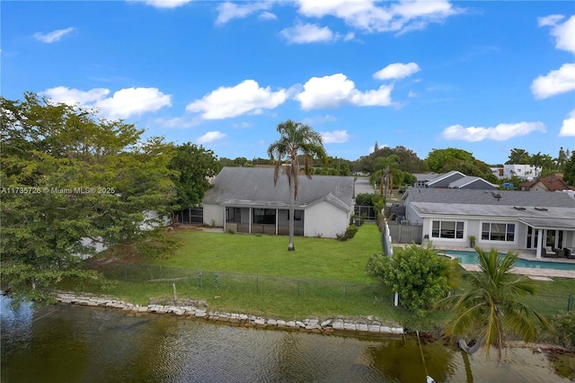 rear view of property with a yard, a water view, a fenced backyard, and an outdoor pool