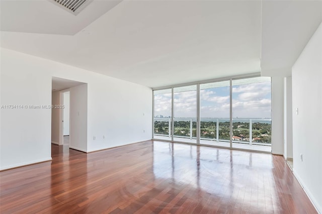 spare room with hardwood / wood-style flooring and a wall of windows