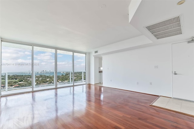 unfurnished room with a wall of windows and hardwood / wood-style floors